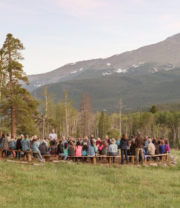 People gathered around a firepit staring out at the mountains